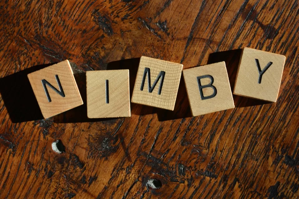 NIMBY spelled out in Scrabble tiles on a wood table